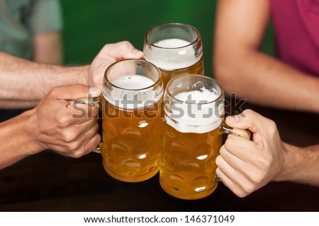 Cheers! Close-up of three hands holding beer mugs