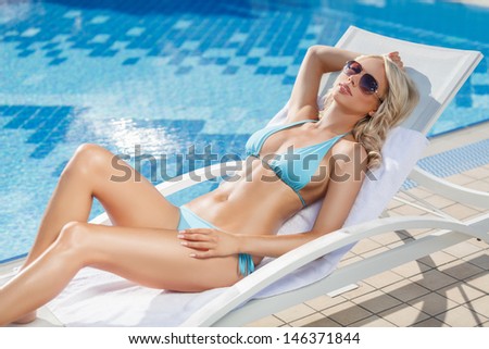 Relaxing on the deck chair. Beautiful young women relaxing on the deck chair near the pool