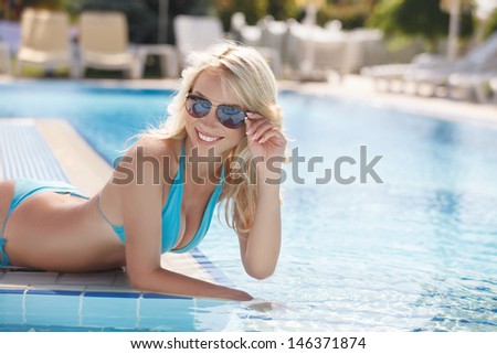 Having fun on the poolside. Side view of beautiful young women in bikini lying on the poolside and smiling at camera