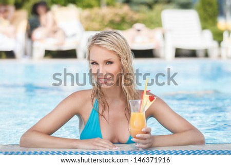 Women drinking cocktail in pool. Portrait of beautiful young women drinking cocktail on the poolside