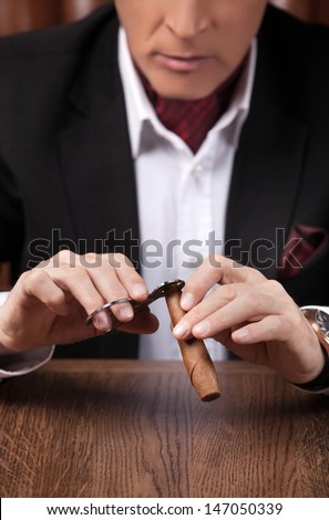Man cutting a cigar. Successful mature man in formalwear cutting a cigar