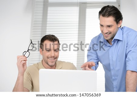 Good results! Two cheerful business people discussing something on the computer and smiling