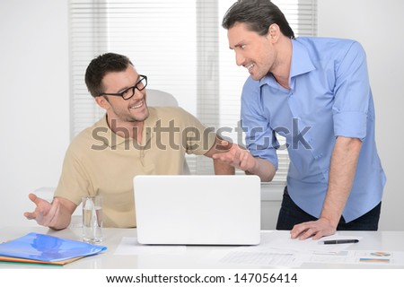 Discussing the problem. Two cheerful business man discussing something on the computer