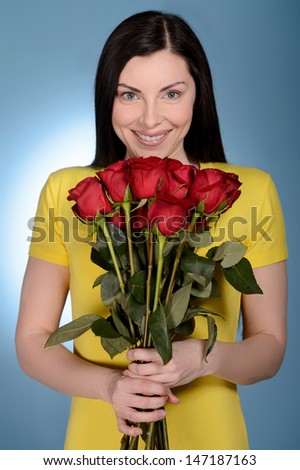 Women with bunch of roses. Beautiful middle-aged women holding a bunch of red roses while isolated on blue