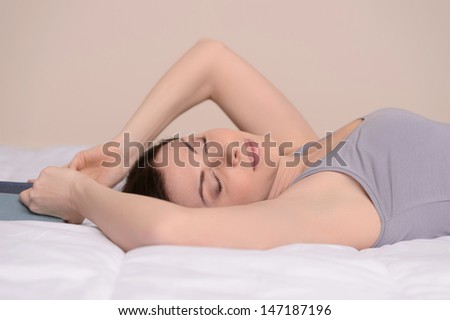 Relaxing on sofa. Beautiful middle-aged women sleeping on the sofa and holding a book in her hands