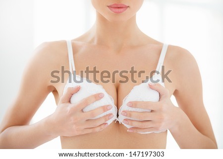 Pushing up. Cropped image of women holding her hands on the bra cups and pushing them up