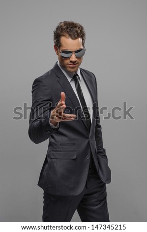 YouÃ?Â¯Ã?Â¿Ã?Â½e the next! Confident young businessmen in sunglasses standing isolated on grey and pointing on camera