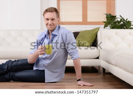 Drinking coffee at home.  Cheerful young men sitting on the floor and drinking coffee