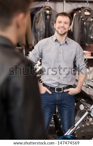 Meeting customer. Cheerful young sales executive meeting customer at the motorcycle shop