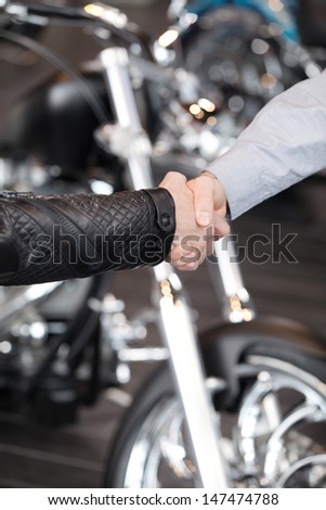 Good deal. Close-up of handshaking with a motorcycle on the background