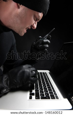 Computer hacking. Close-up of angry criminal using computer
