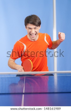 I won! Happy young men gesturing with a table tennis racket in his hand