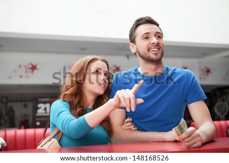 Loving couple at the restaurant. Young loving couple buying movie tickets