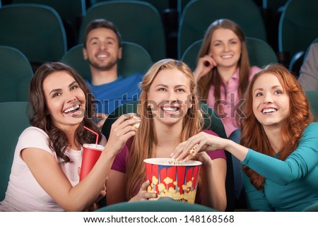 Friends at the cinema. Happy young people watching movie at the cinema and laughing