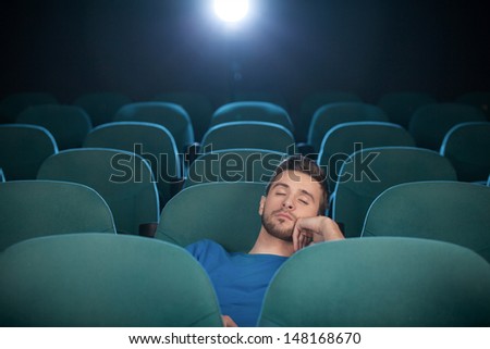 Sleeping at the cinema. Young men sleeping at the cinema and holding his hand on chin