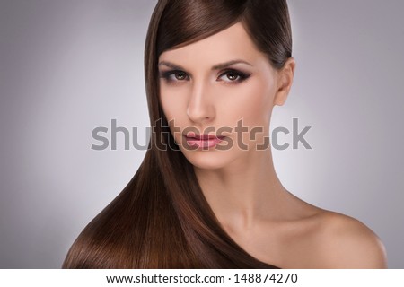 Hairstyle. Portrait of attractive young women with beautiful hair looking at camera while isolated on grey