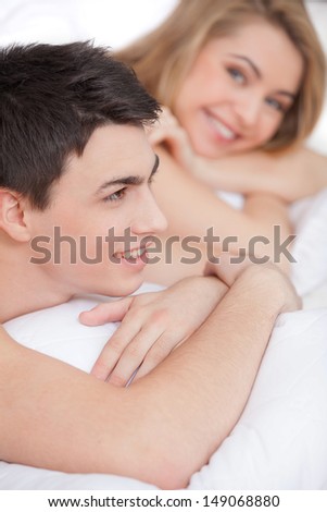 Loving couple in bed. Beautiful young loving couple lying on bed and smiling