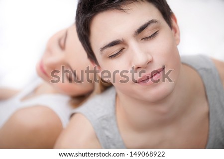 Loving couple relaxing together. Top view of young loving couple relaxing while sitting back to back and keeping their eyes closed