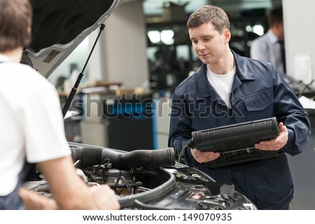 Mechanics at work shop. Two confident auto mechanics working at the repair shop