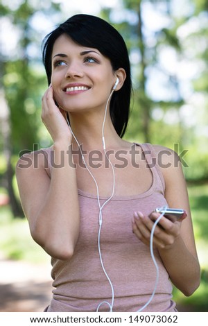 Beautiful women in park. Beautiful young women in headphones listening to the music while walking in park