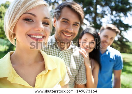 Friends in a row. Young cheerful people standing in a row and smiling