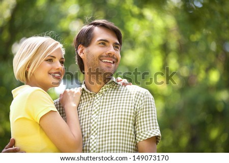 Loving couple in park. Happy young couple standing close to each other and smiling