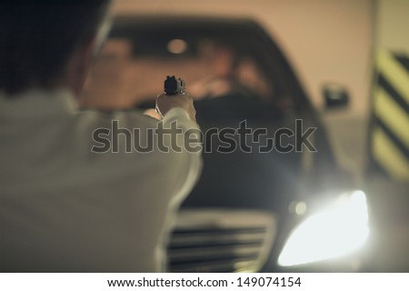 Killer with gun. Rear view of men with handgun aiming the car driver