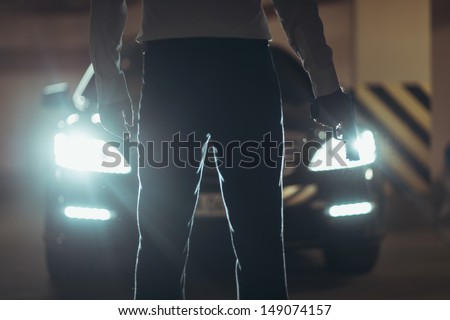 Killer with handgun. Cropped image of men with handgun standing in front of car