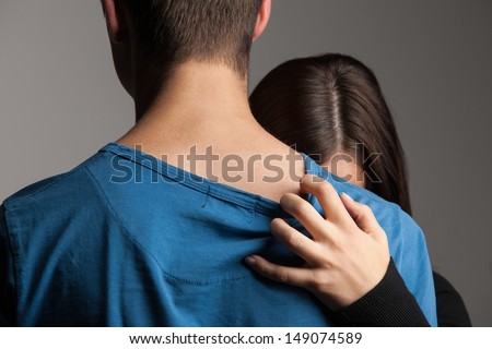 Beak-up. Young couple hugging while isolated on grey