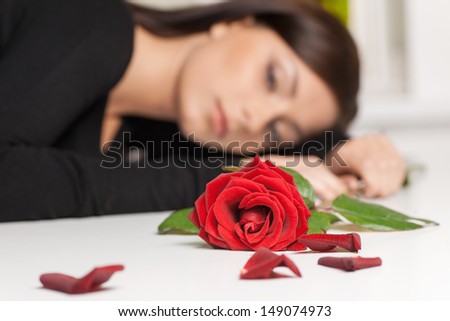 Women and rose. Beautiful young woman sitting at the table with a red rose lying on it