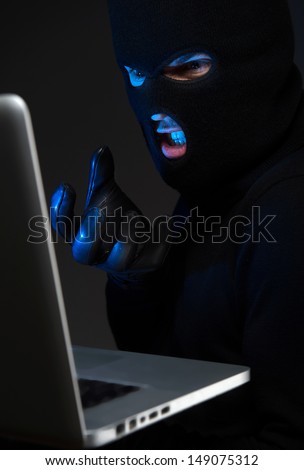 Computer hacking. Angry young men in balaclava gesturing and looking at the computer monitor