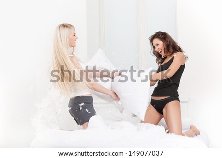 Pillow fight. Beautiful young women fighting with pillows