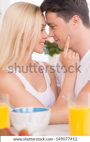 Loving couple. Young loving couple looking at each other while having breakfast together