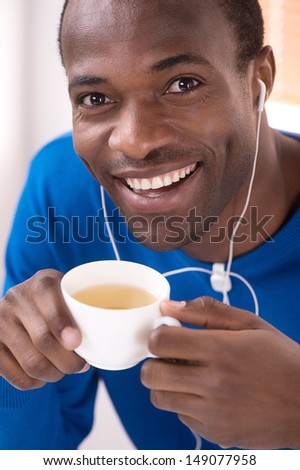 Enjoying his free time at home. Top view of cheerful African descent men listening to the music and drinking coffee