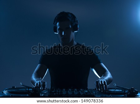DJ playing music. Confident young DJ spinning on turntable while standing isolated