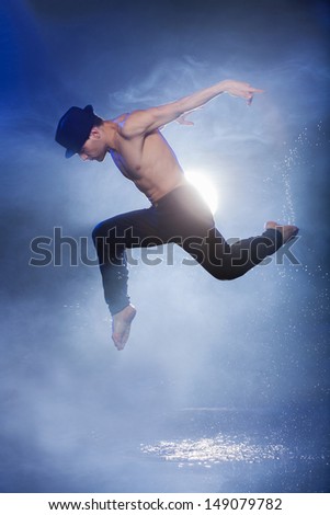 Wet dancer. Young male dancer in black fedora dancing on the wet floor