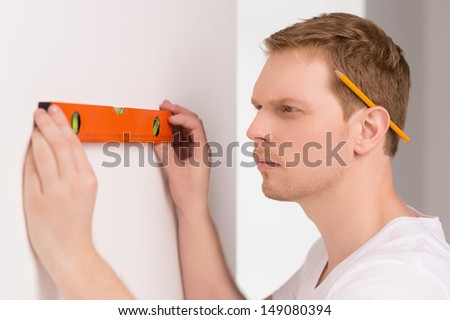 Handyman measuring wall. Confident craftsperson measuring the wall and looking at camera