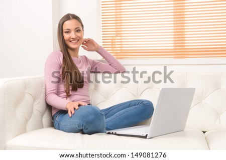 Working at the computer at home. Beautiful young women working at the computer while sitting on the couch