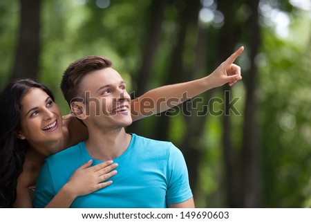 Couple having fun in park. Young loving couple having gun at park while woman pointing away with finger