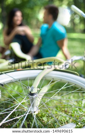 Relaxing In Park Together. Young Couple Sitting Close To Each Other In Park While Bicycle Lying On The Foreground