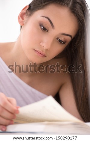 Reading an interesting book. Beautiful young woman reading a book