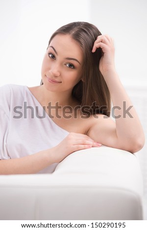 Beautiful young women. Beautiful young women sitting on the couch and holding her hand in hair