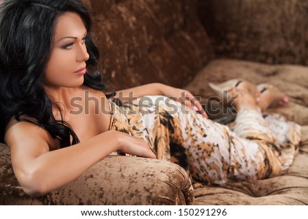 Beauty on the couch. Side view of beautiful young black hair woman lying on the couch and looking away