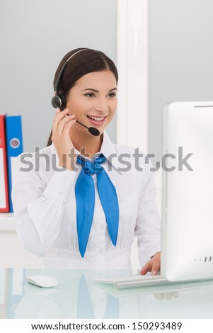 Beautiful customer service representative. Cheerful young female customer service representatives in headset working at the computer and smiling