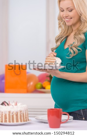 Pregnant woman eating cake. Cheerful pregnant woman eating cake and smiling