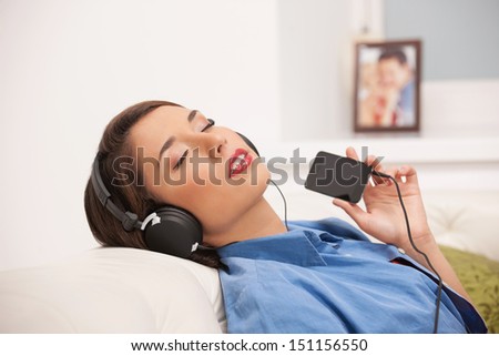 Listening to the music. Beautiful young woman in headphones listening to the music and keeping her eyes closed