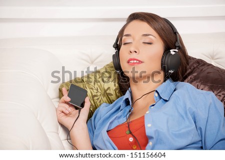 Listening to her favourite music. Beautiful young woman listening to the music and keeping her eyes closed