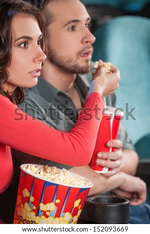 Great movie! Close-up of young couple feeding each other while watching movie at the cinema