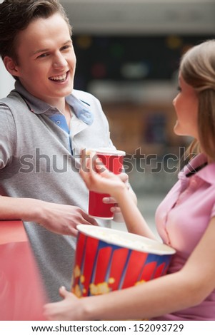Couple talking. Cheerful young couple drinking soda and eating popcorn