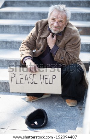 Please help. Depressed senior tramp in dirty wear sitting on stairs and holding poster